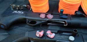 Two shotguns with pink earplugs with eye protection.