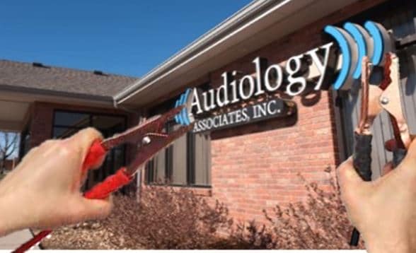 A person with jumper cables promotes "Jump Start Your Practice with Recreational Audiology" at Audiology Inc.