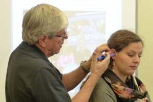 A woman is being fitted for custom hearing protection.