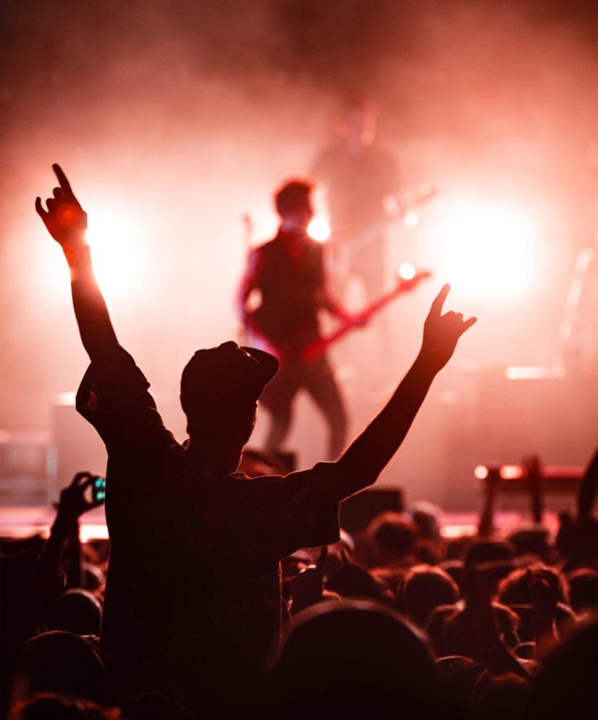 A crowd at a concert lifting their hands in the air.