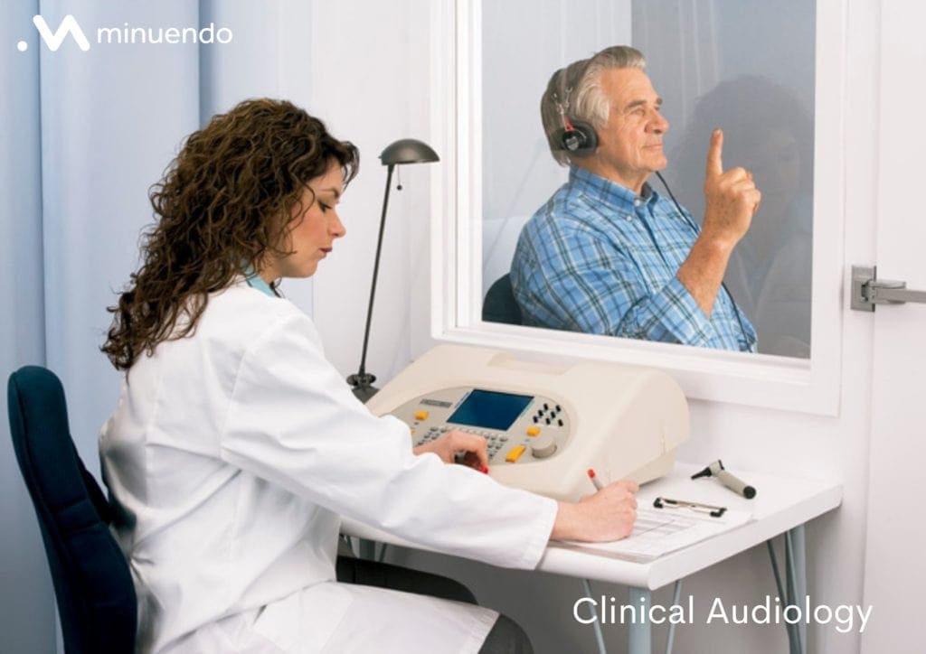 An image of a woman in a audiologist's office measuring the hearing of a man in a blue shirt.