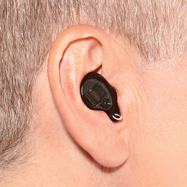 A shot from behind someone’s ear featuring black, nearly invisible Soundgear Phantom hearing aids in use.