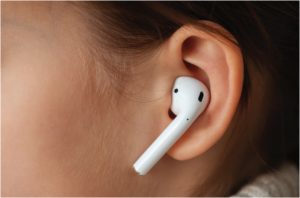 Apple airpods in the ear of a young girl.