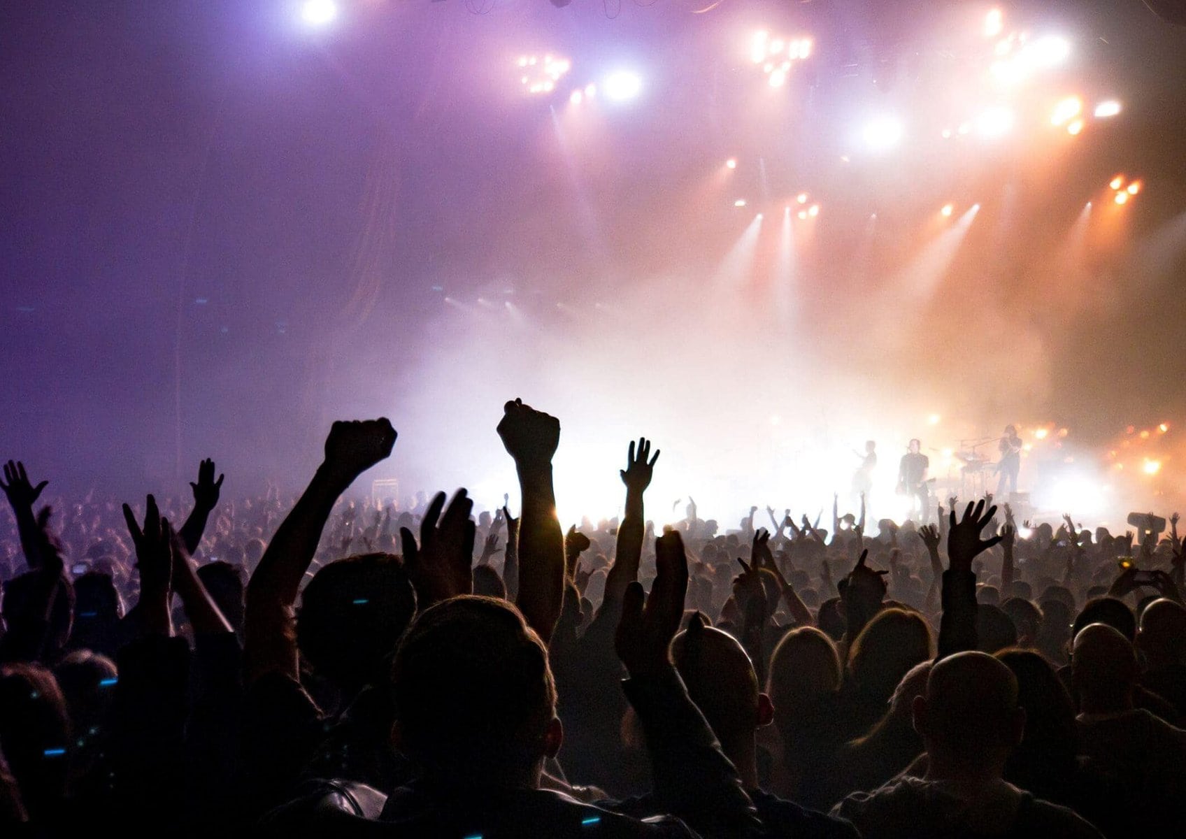 A loud concert with people raising their hands in the air.