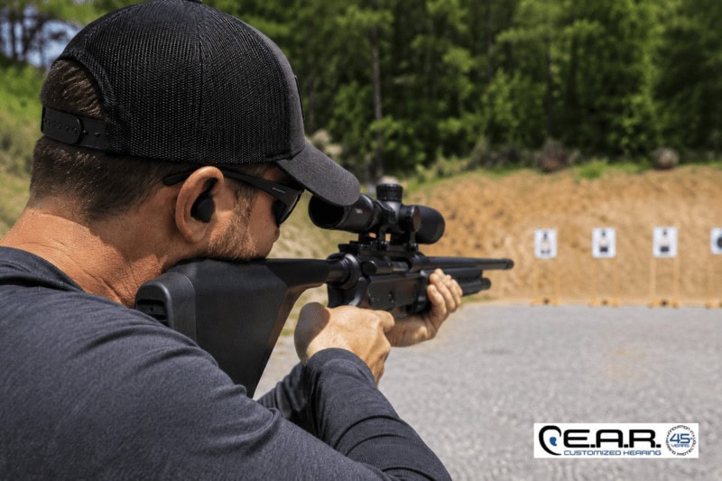 Shooter wearing digital hearing protection during target practice at an outdoor shooting range