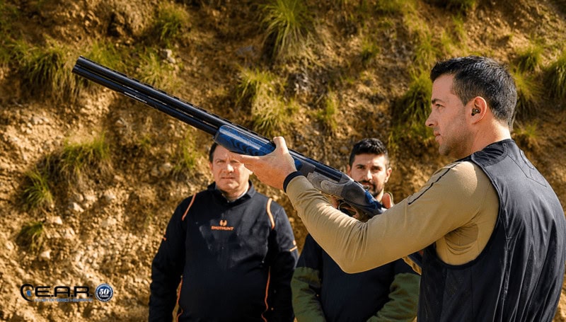 Competitive shooter using electronic hearing protection at an outdoor shooting range
